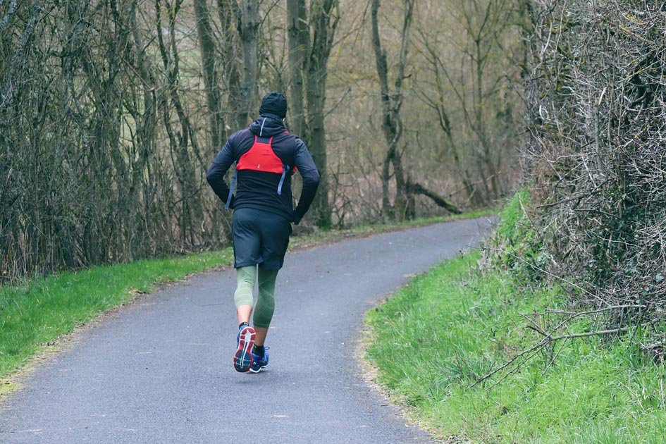 A man walking on a road between woods