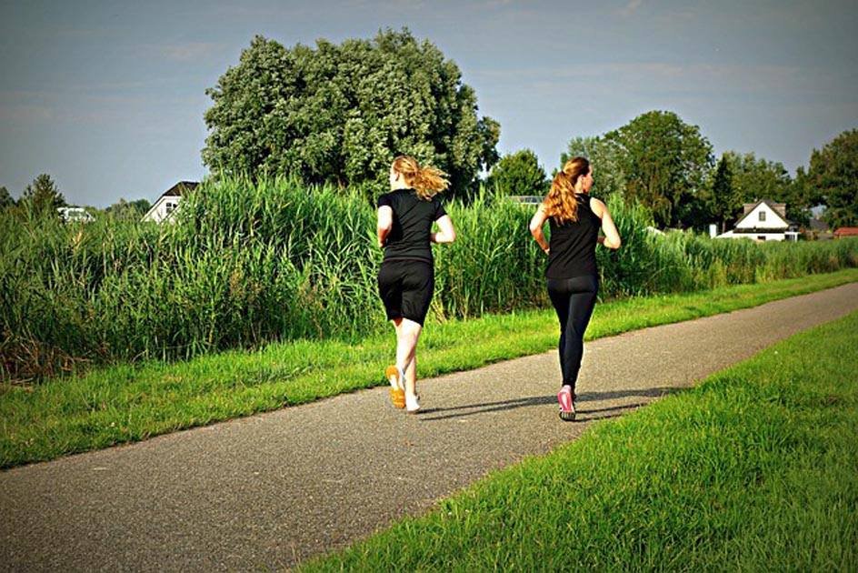 Two women are jogging in a green town